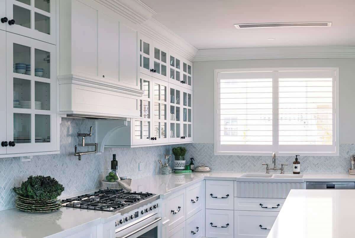 A kitchen with white cabinetry, a gas stove, a sink, and a window with blinds.