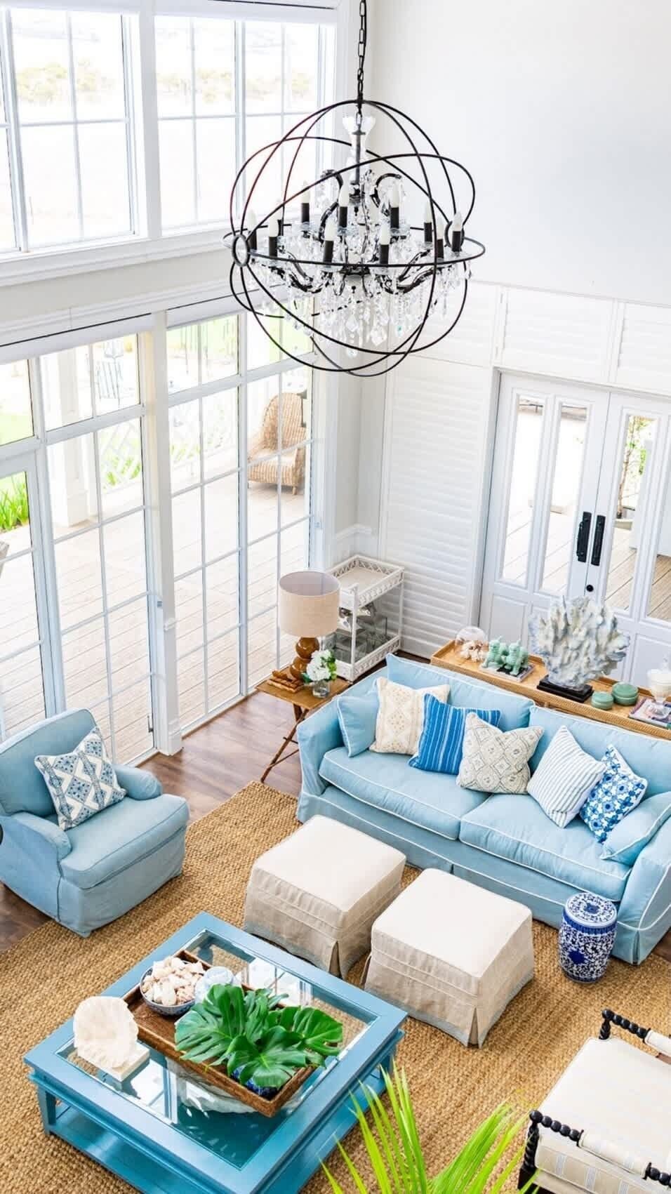 A spacious living room with a large blue sofa, a coffee table, and a chandelier.