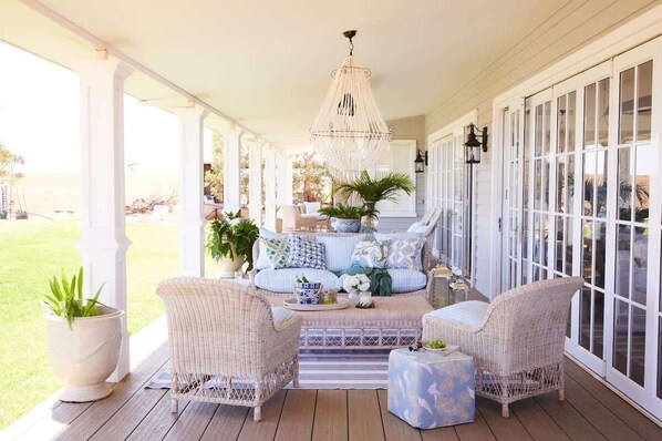 A covered porch with wicker furniture, a chandelier, and a view of the outdoors.