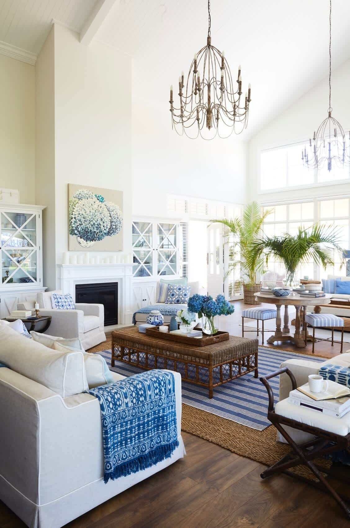 A spacious living room with a fireplace, a large chandelier, and a view of the outdoors.