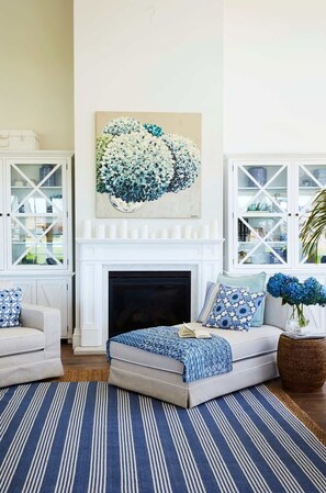 A living room with a fireplace, two sofas, a large floral artwork, and a patterned rug. - Hamptons Farm Estate—Luxe Retreat & Elegant Events (Wongamine)