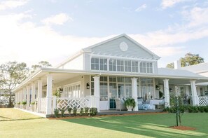 A two-story house with a covered porch, large windows, and a symmetrical facade.