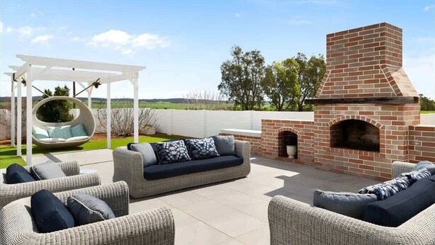 An outdoor patio with wicker furniture, a hanging swing, and a brick fireplace. - Hamptons Farm Estate—Luxe Retreat & Elegant Events (Wongamine)