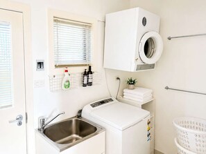 A laundry room with a washing machine, dryer, and a sink.