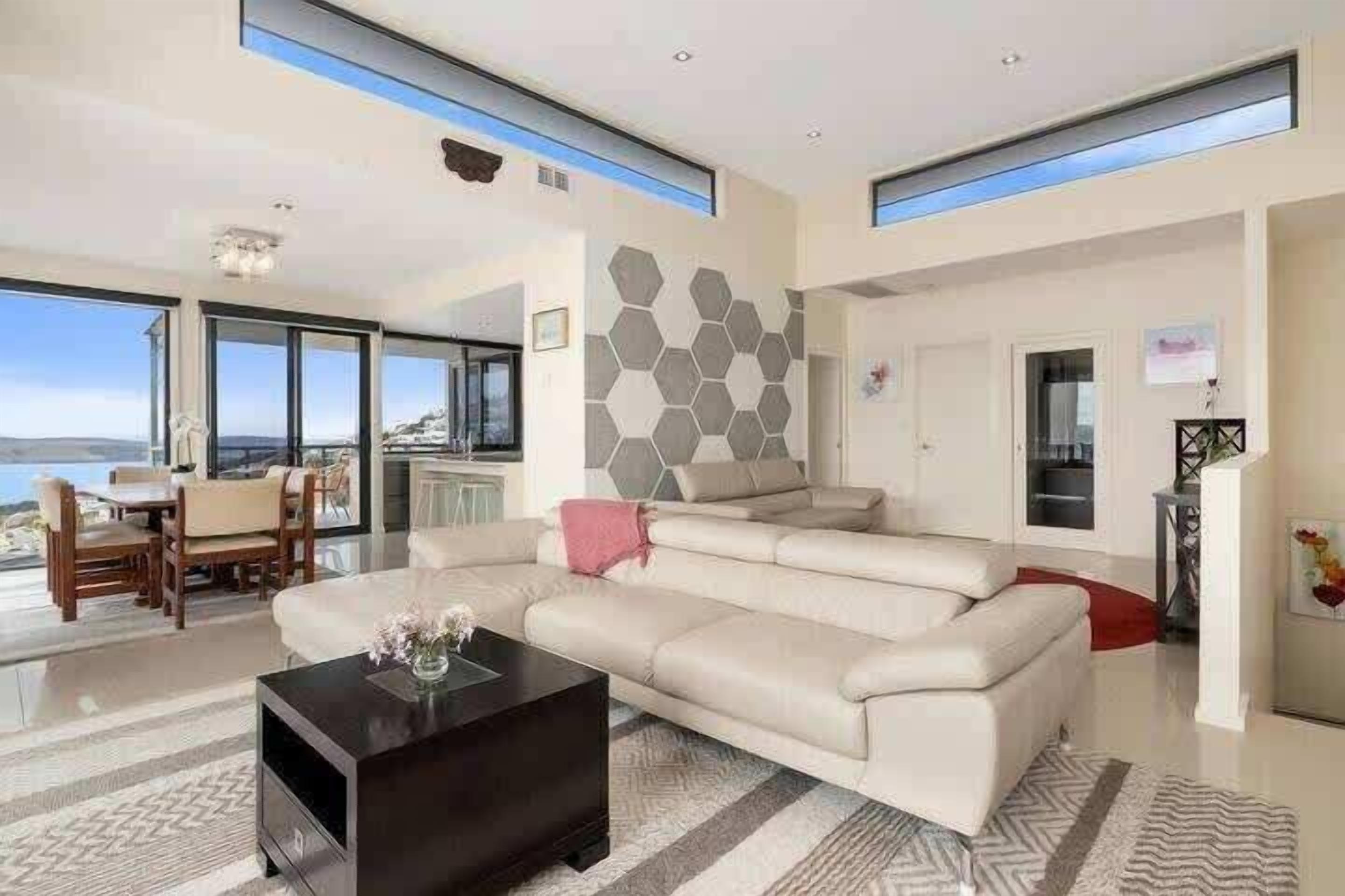 Un salon moderne avec un grand canapé, une table basse et un coin repas avec des chaises.