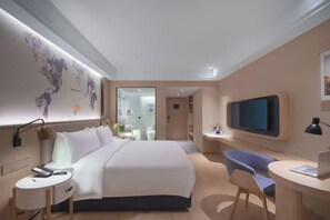 A modern hotel room with a large bed, a desk, a chair, a TV, and a world map on the wall. - Kyriad Marvelous Hotel (Suzhou Wujiang People's Square) (Suzhou)