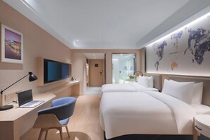 A modern hotel room with a desk, laptop, chair, two beds, and a large world map on the wall. - Kyriad Marvelous Hotel (Suzhou Wujiang People's Square) (Suzhou)