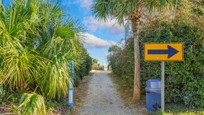 Un chemin menant à un bâtiment, avec un panneau indicateur.