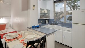Cocina compacta con comedor, que incluye una mesa puesta con platos, tazas y una tetera.