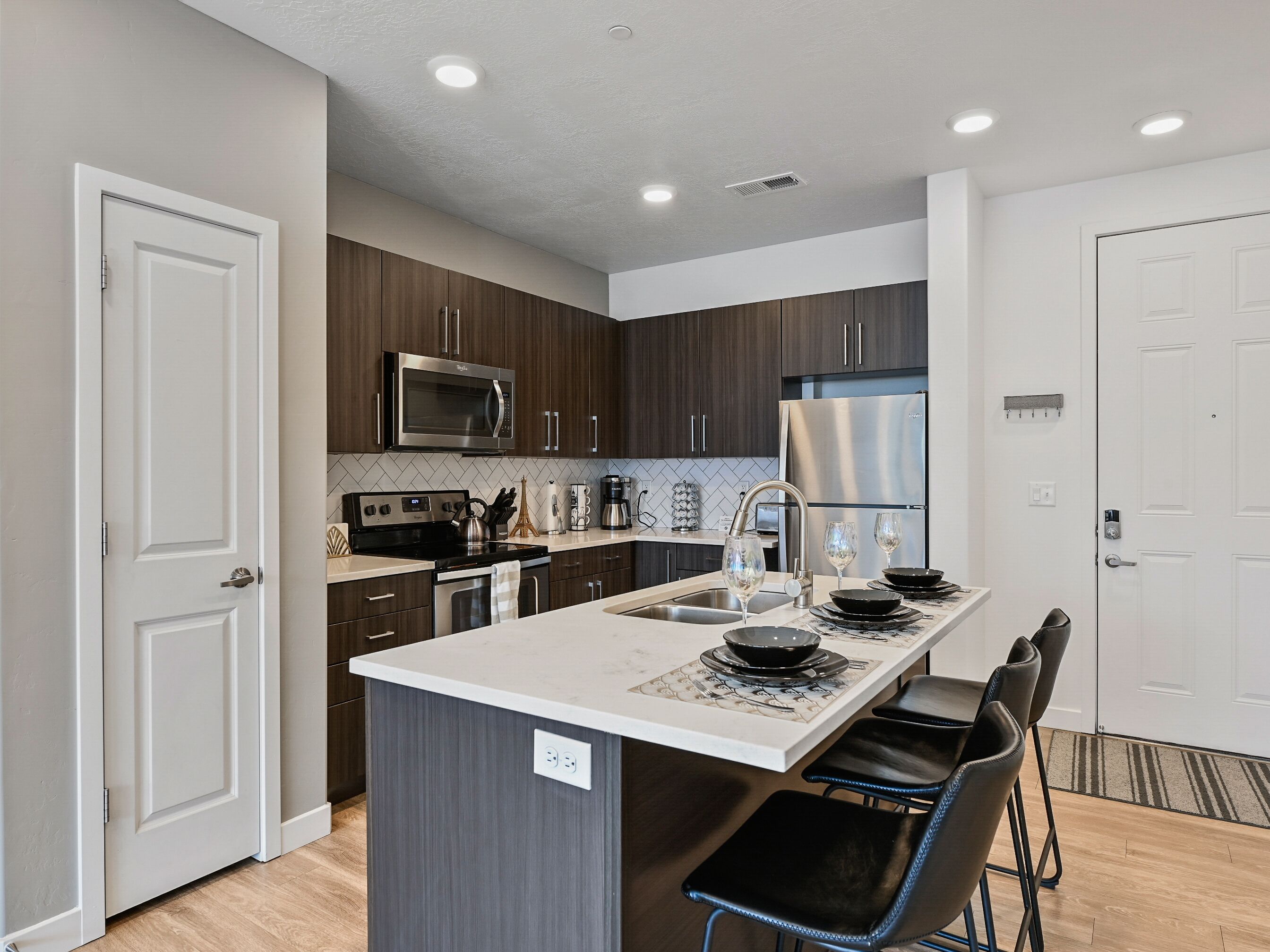 A modern kitchen with dark wood cabinets, stainless steel appliances, and a central island with bar stools.