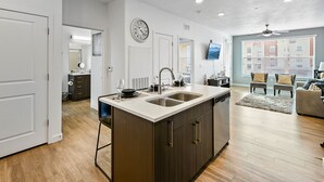 A modern kitchen with a central island, a dining area with a sofa, and a living room with a TV.
