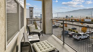 A balcony with outdoor seating, a view of a parking lot, and distant mountains.
