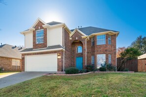 A two-story house with a garage, brick exterior, and a well-maintained lawn.