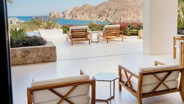 Un espace extérieur aménagé avec du mobilier en bois, offrant une vue sur la mer et les montagnes.