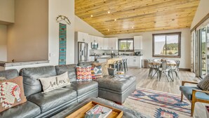 A modern living room with a leather sofa, a dining area, and a kitchen.