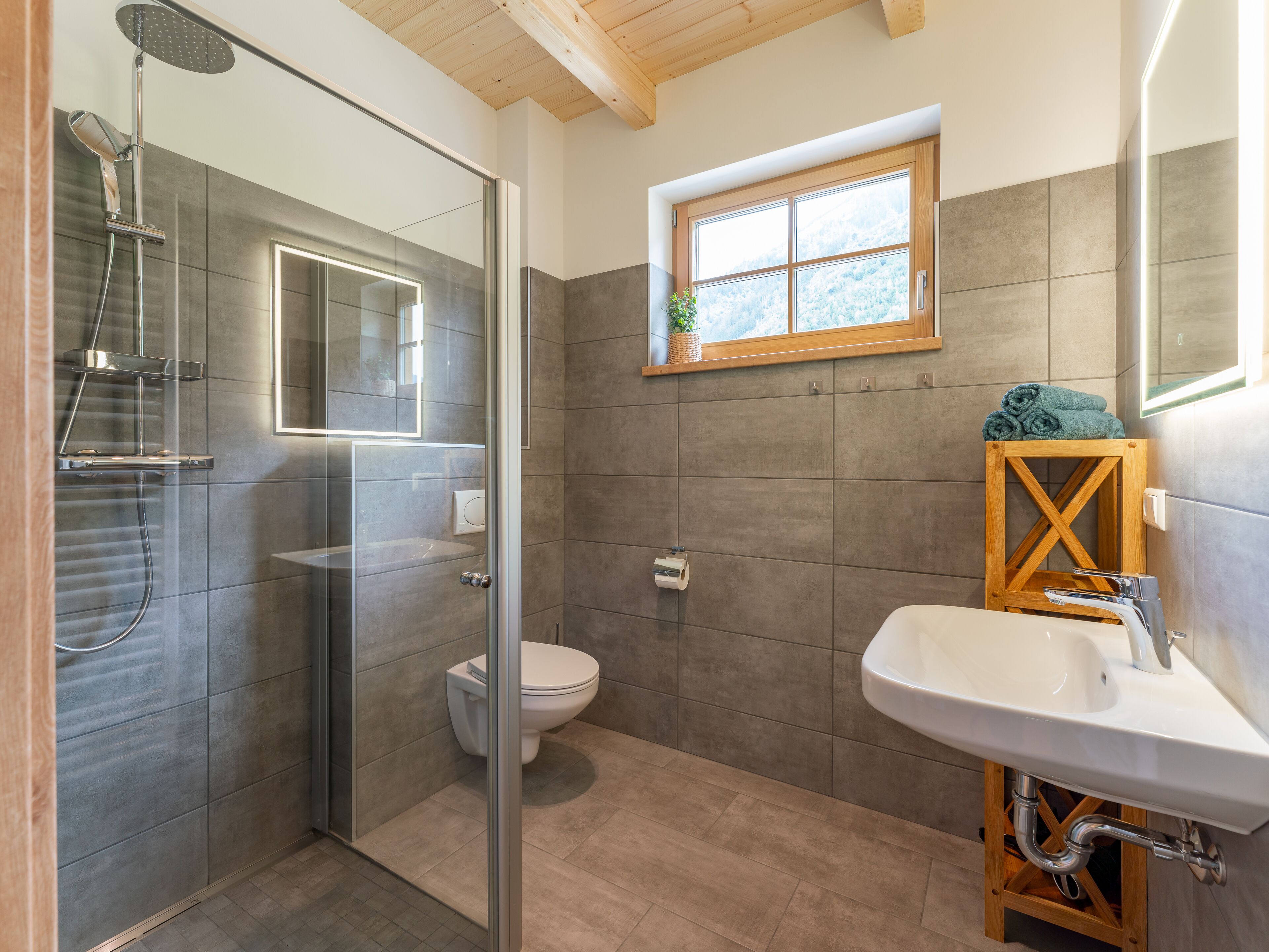 A modern bathroom with a glass-enclosed shower, a toilet, and a sink with a wooden cabinet.