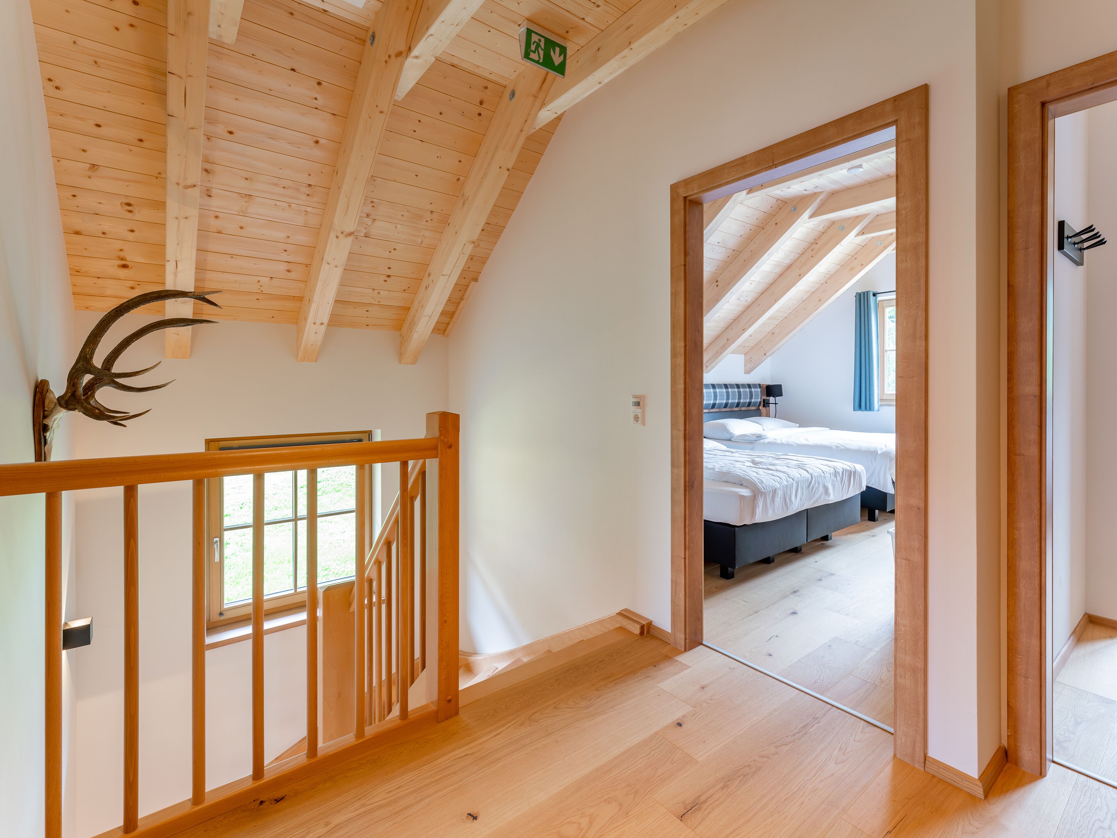 Una scala in legno conduce a una camera da letto con un letto e una finestra.