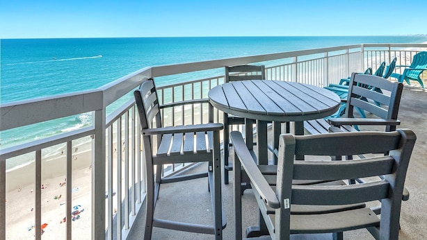 A balcony with a view of the beach and ocean.