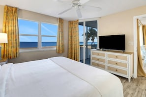 Ett hotellrum med en stor säng, en tv på en byrå och en balkong med utsikt över havet.