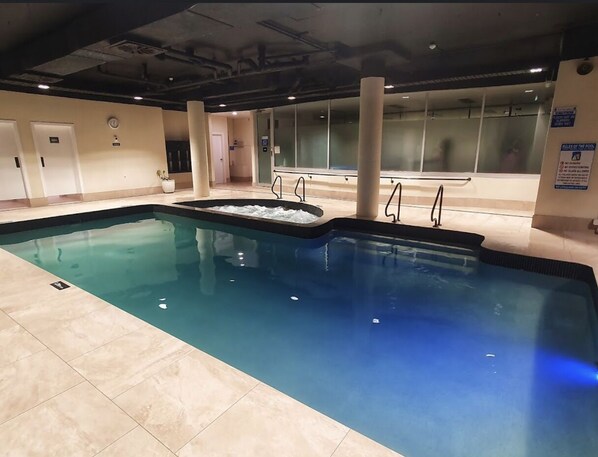 Swimmers can enjoy a rectangular pool surrounded by a tiled floor.