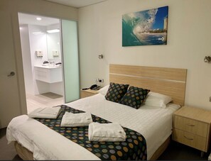 Cozy retreat with a neatly made bed, wooden nightstand, and cityscape painting.