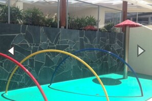 Swimmers can enjoy the pool surrounded by a geometric stone wall and shaded seating.