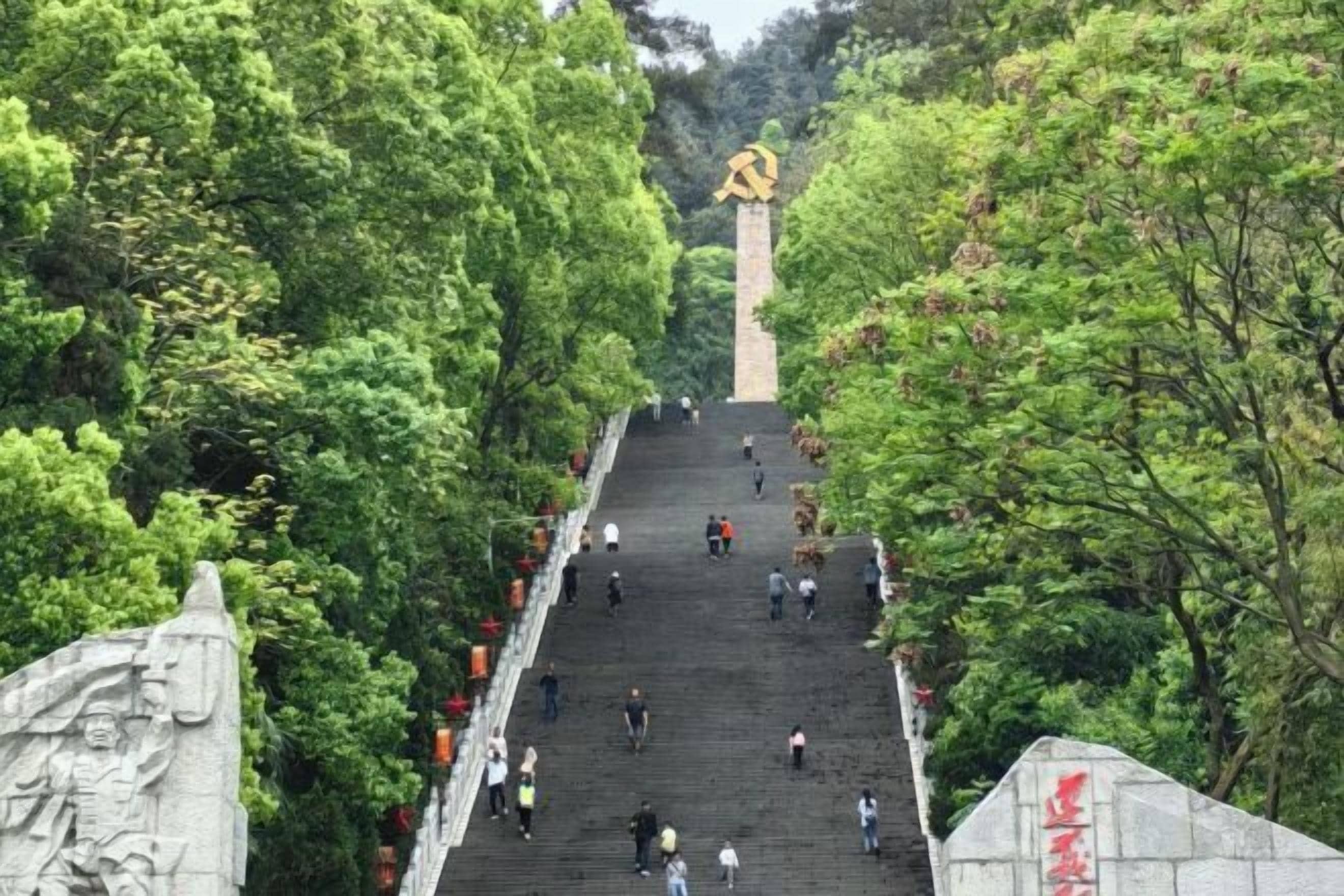 A wide staircase surrounded by lush greenery, leading to a monument at the top.