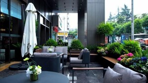 An outdoor seating area with modern furniture, a round table, and a variety of plants. - New Joy Hotel (Internatial Trade Spring Department Store Shopping) (Zunyi)
