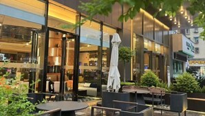 An outdoor seating area with tables and chairs, a glass wall, and a building with a modern design. - New Joy Hotel (Internatial Trade Spring Department Store Shopping) (Zunyi)