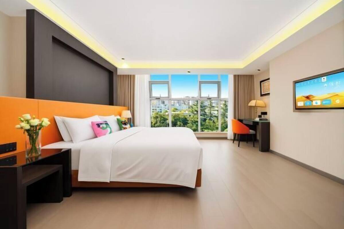 A modern hotel room with a large bed, a desk, and a TV.