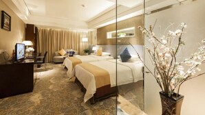 A hotel room with two beds, a desk, a chair, a glass partition, and a vase with flowers. - New Joy Hotel (Internatial Trade Spring Department Store Shopping) (Zunyi)