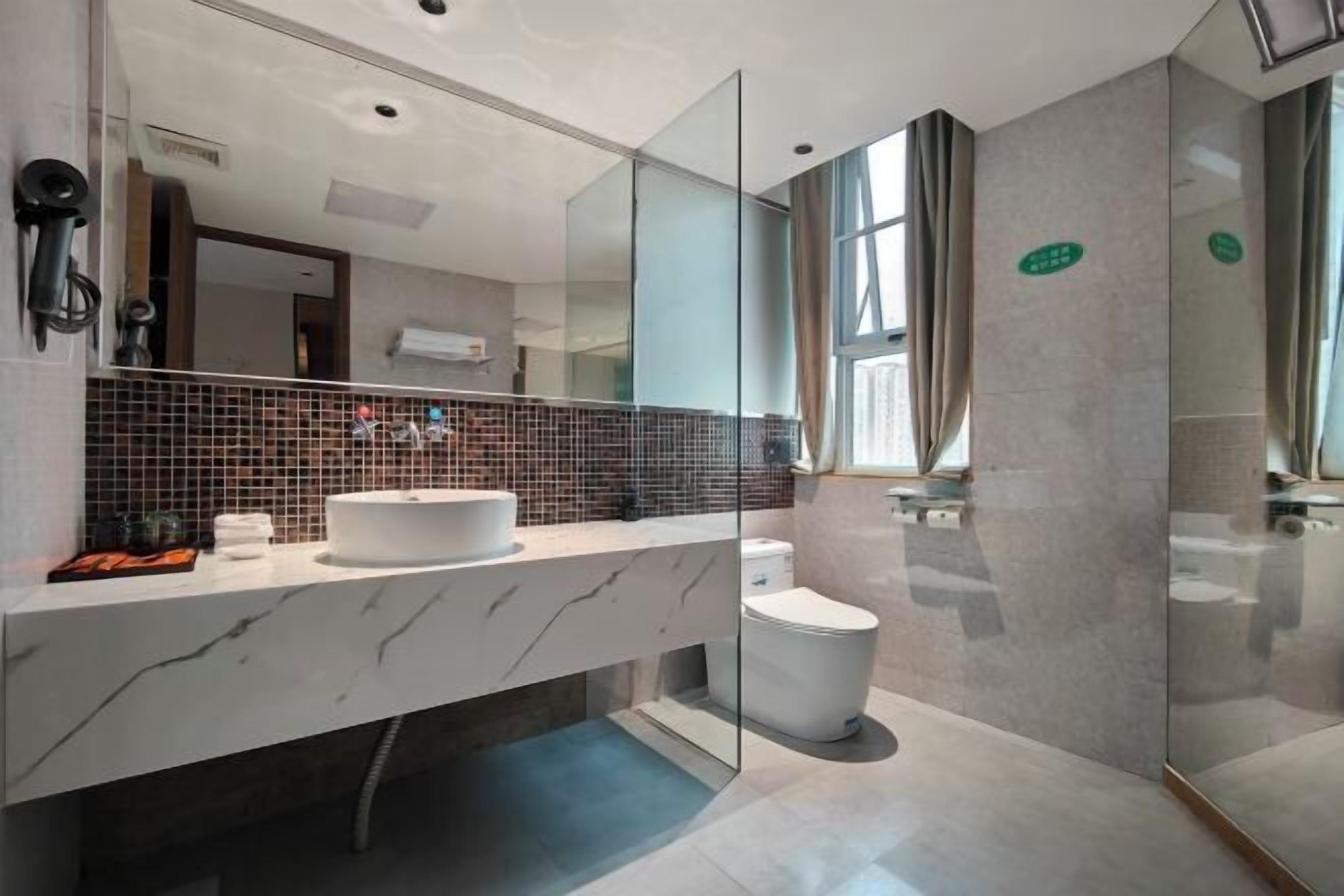 Une salle de bain moderne avec un meuble-lavabo en marbre blanc, une cabine de douche en verre et un pare-splash en carrelage.