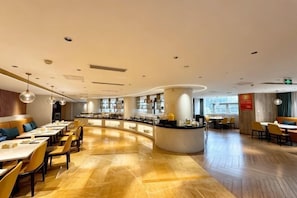 A modern restaurant with a curved counter, wooden flooring, and a variety of seating options. - New Joy Hotel (Internatial Trade Spring Department Store Shopping) (Zunyi)
