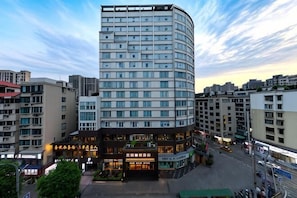 A modern hotel with a curved facade, multiple floors, and a ground-level commercial area.