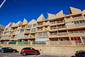 A multi-story building with a modern architectural design, featuring balconies and a stone facade.