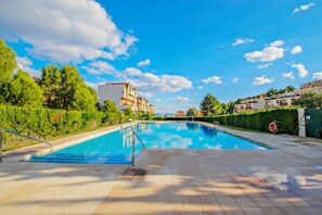 A swimming pool with a clear blue sky and buildings in the background.
