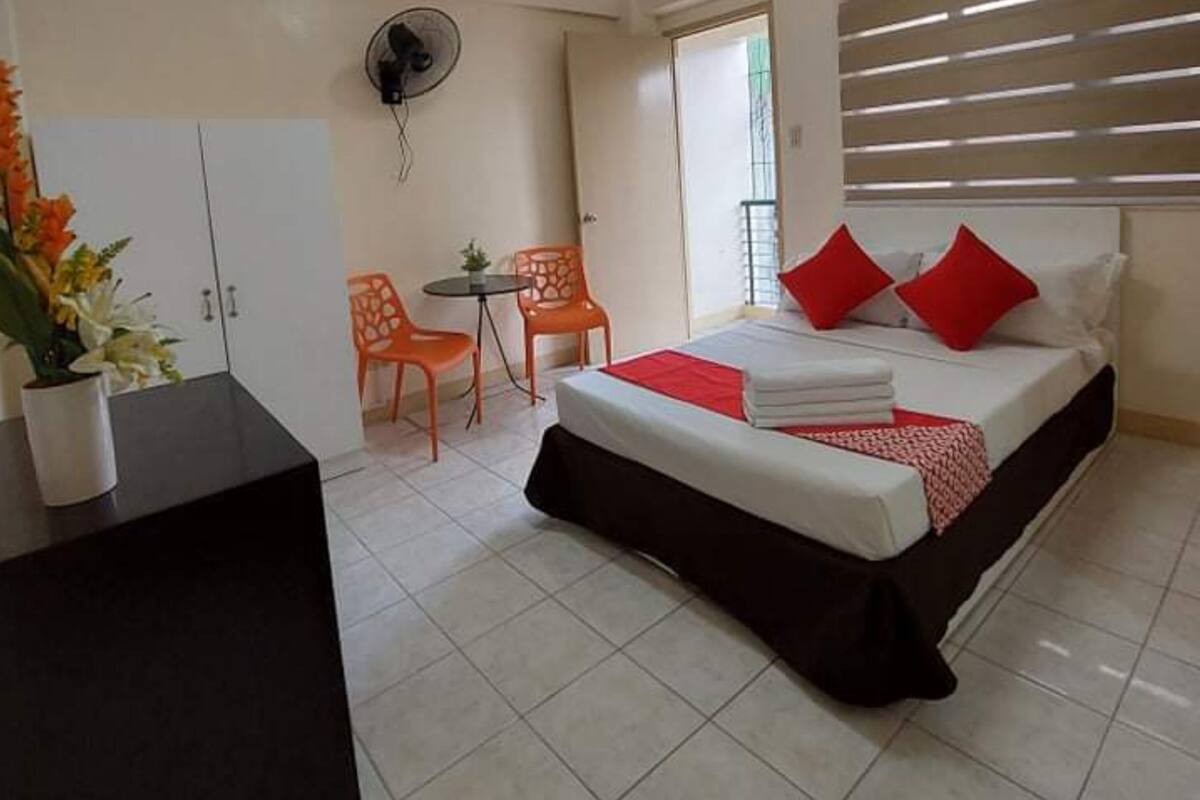 A hotel room with a bed, a desk, a chair, and a small table.