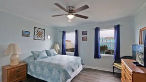 A bedroom with a bed, a ceiling fan, a window with curtains, and a dresser. - "SeaQuest East" -2nd Row Pet Friendly Duplex, 4 Bedrooms / 3 Bathrooms (Holden Beach)