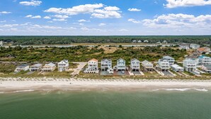 Et kystnære boligområde med ejendomme direkte til stranden, herunder huse med altaner og en strand i forgrunden.