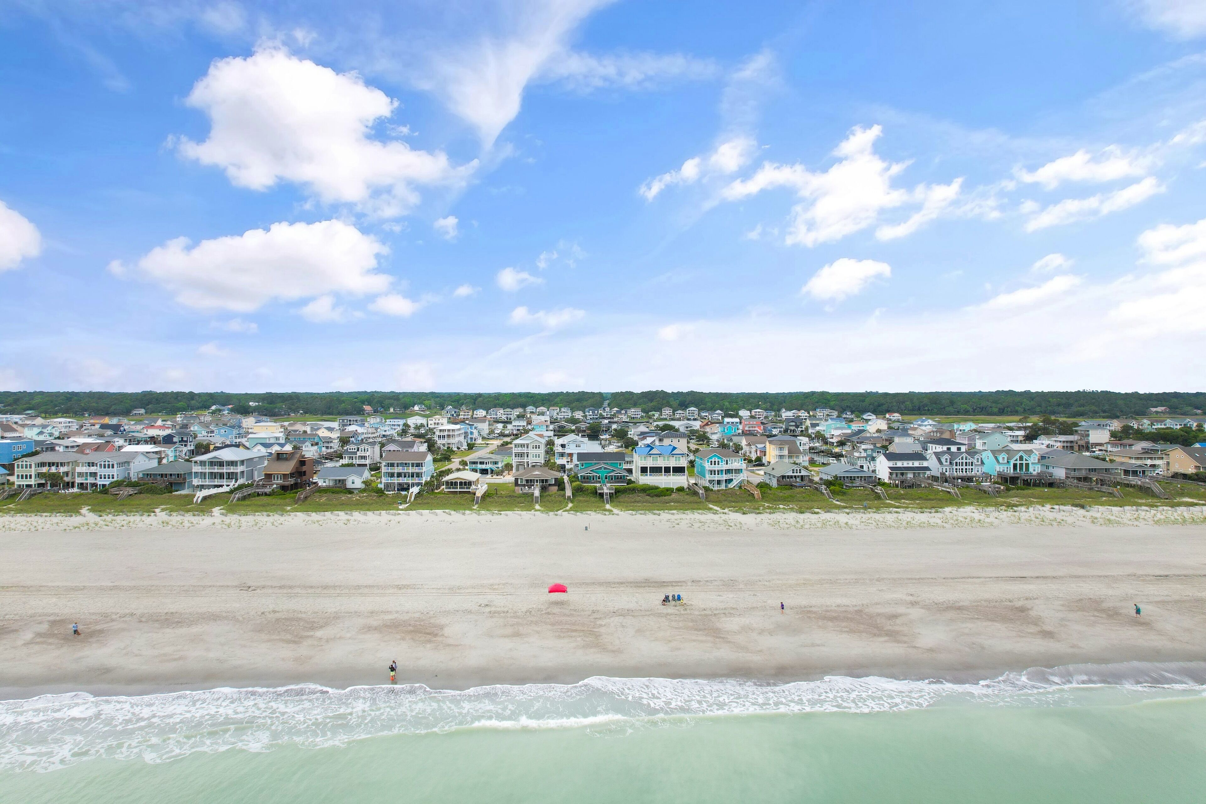 En kystby med huse ud til stranden og en sandstrand.