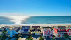 A row of colorful beach houses with a view of the ocean. - "Goin' Coastal" - Oceanfront Home, 4 Bedrooms / 4.5 Bathrooms (Holden Beach)