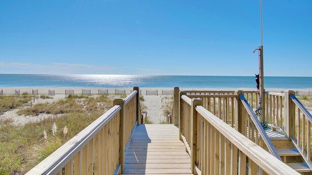A wooden boardwalk leading to a beach with a clear sky. - "Goin' Coastal" - Oceanfront Home, 4 Bedrooms / 4.5 Bathrooms (Holden Beach)
