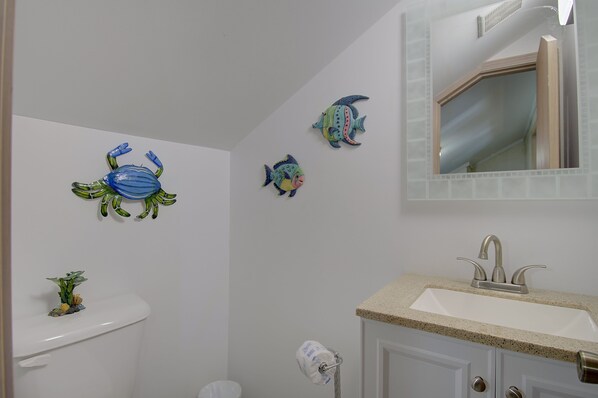 Un baño con inodoro, lavamanos y decoración de peces en la pared.