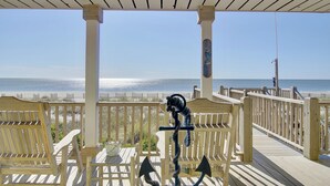 A wooden deck with a railing overlooking a beach. - "Goin' Coastal" - Oceanfront Home, 4 Bedrooms / 4.5 Bathrooms (Holden Beach)