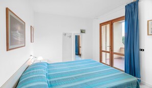 A bedroom with a bed, a door leading to a bathroom, and a window with curtains.