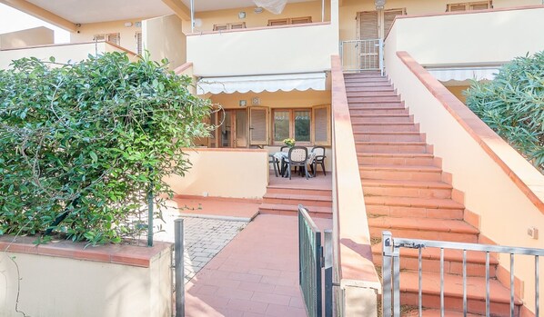 A multi-level building with a staircase leading to a covered outdoor area with tables and chairs.