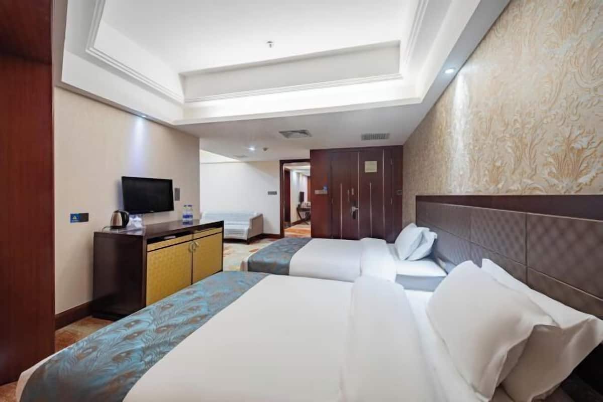 A hotel room with two beds, a television, a desk, and a wardrobe.
