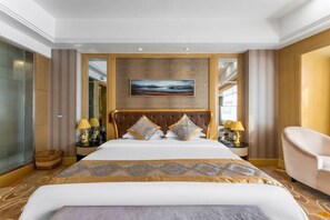 A hotel room with a large bed, a headboard with a painting, two bedside tables with lamps, and a chair. - Hanjiang International Hotel (Danjiangkou)