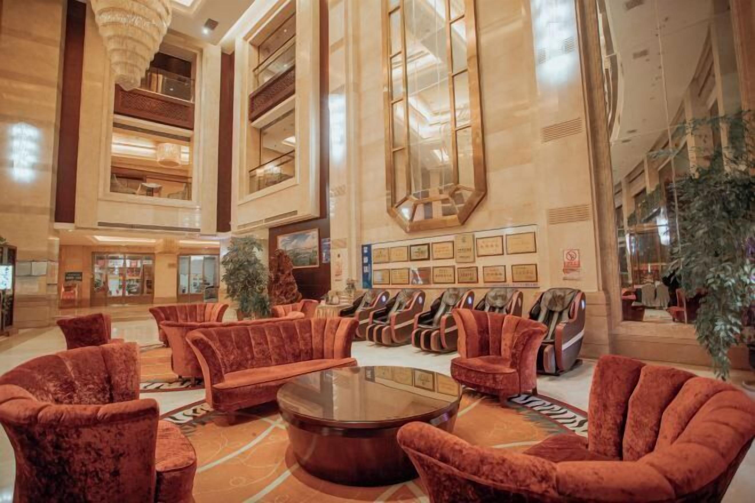 Een ruime lobby met een centrale zithoek, een grote spiegel en een receptiebalie.