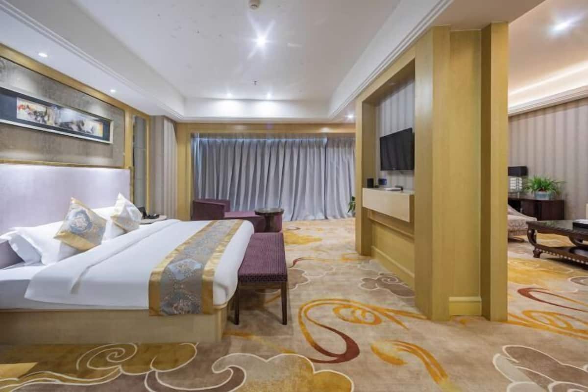 A hotel room with a large bed, a desk, a chair, and a TV.